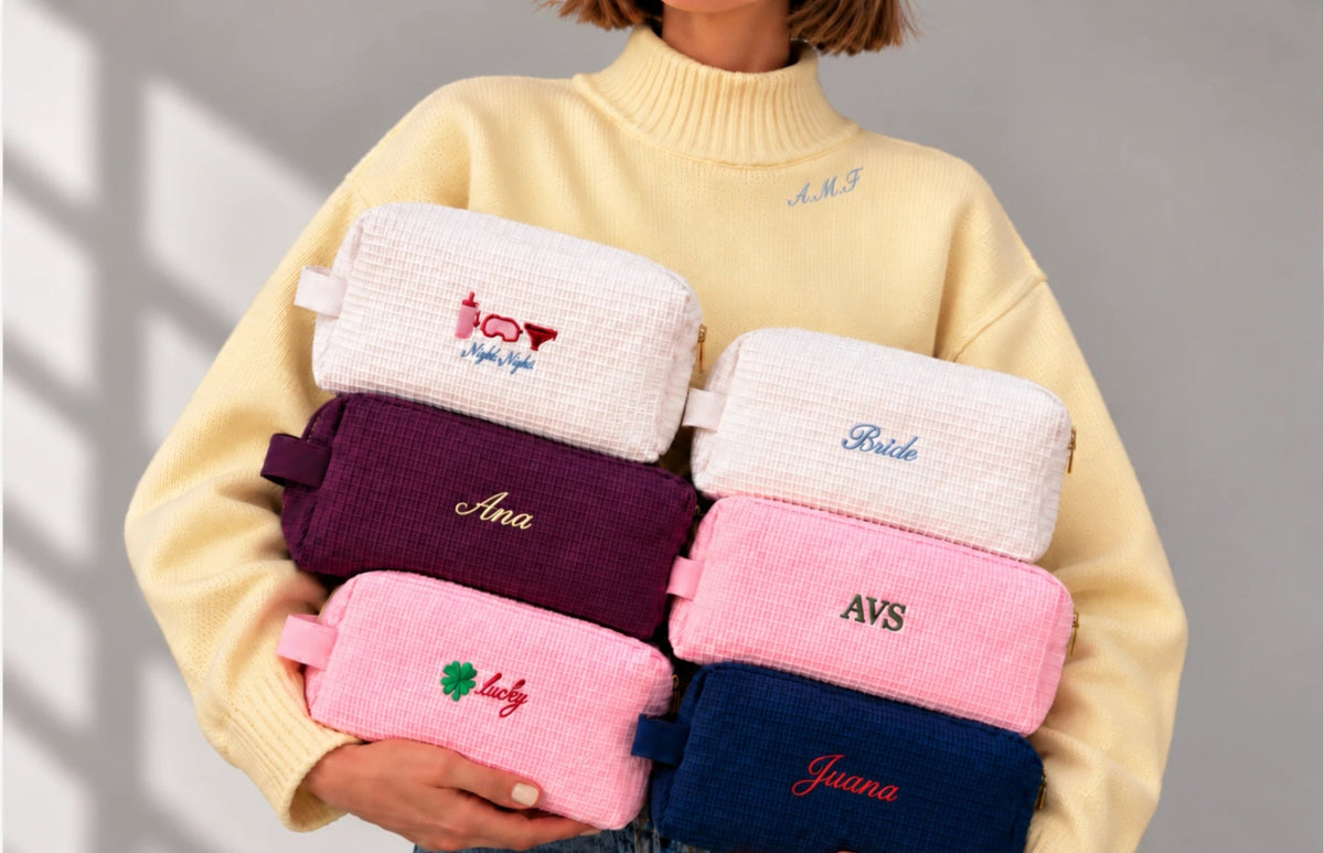 Mujer con suéter amarillo sosteniendo seis pouches waffle con iniciales, nombres e íconos bordados