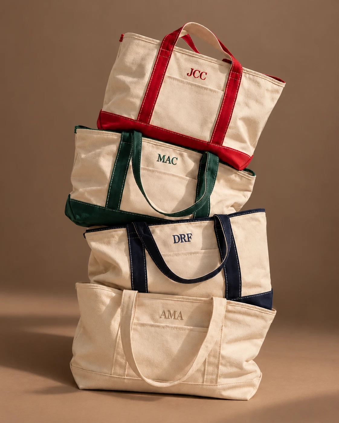 Totes Toluma apilados con iniciales bordadas