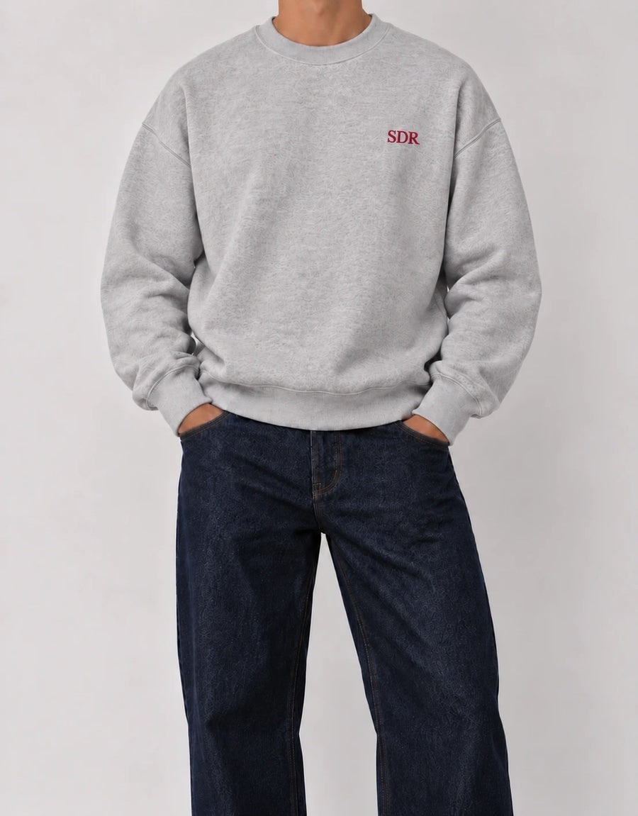 The Classic Crewneck gris con iniciales SDR en hilo rojo, bordado al lado izquierdo del pecho