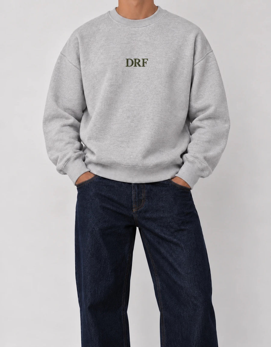 The Classic Crewneck gris con iniciales DRF en hilo verde oliva, bordado al centro del pecho
