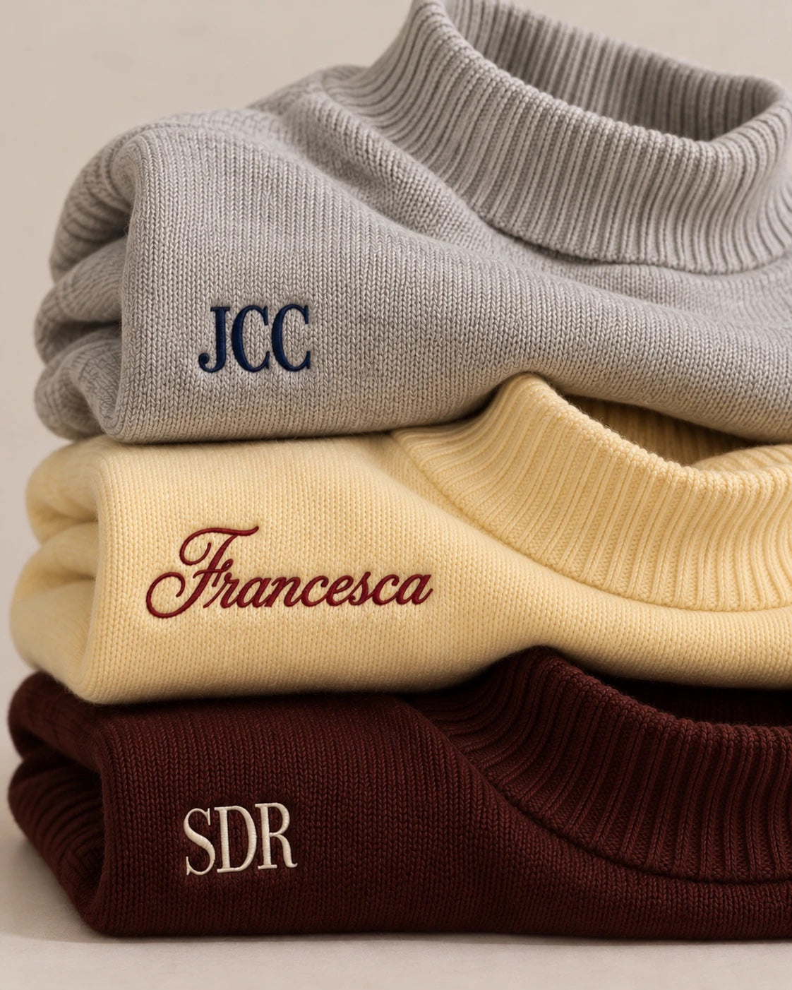 Tres suéteres doblados con JCC, Francesca y SDR bordados